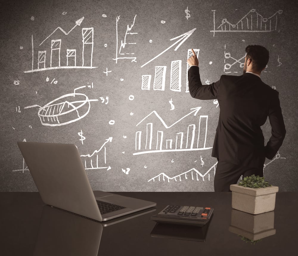 A young marketing office worker drawing pie chart and graph on wall at financial meeting concept